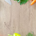 Colorful vegetables and herbs arranged on a rustic wooden surface.