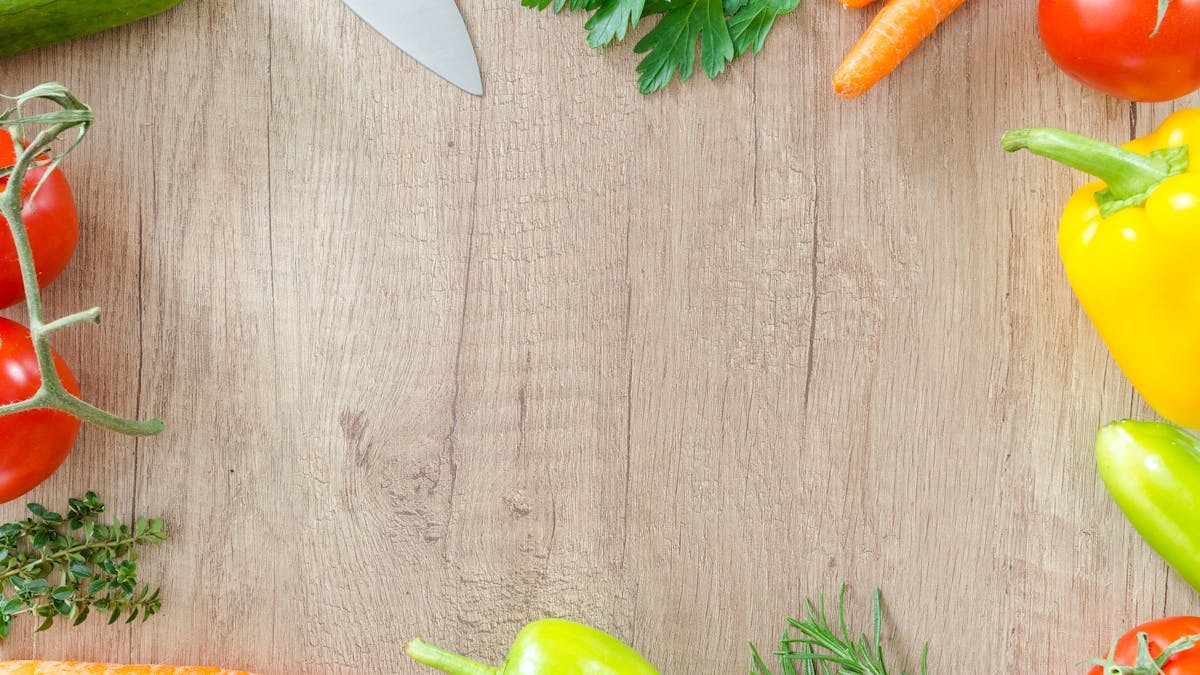 Colorful vegetables and herbs arranged on a rustic wooden surface.